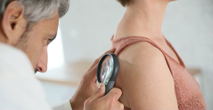 Doctor examining the back of a patient for MOHS