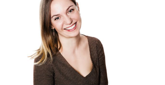 Photo of a female model with shoulder length hair wearing brown blouse against white background