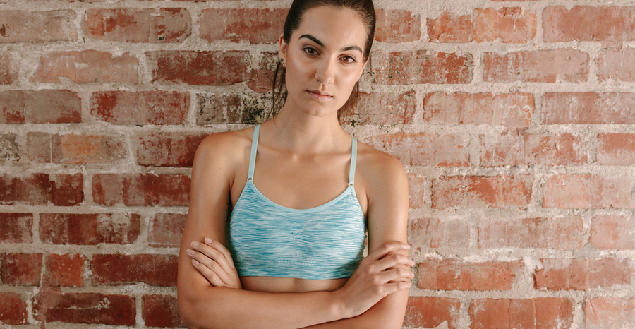 Woman in blue sports bra against a brick wall