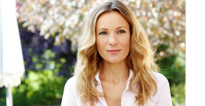 Photo of a beautiful female with blonde wavy hair and wearing a white blouse