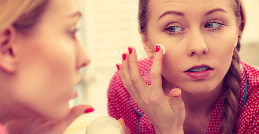 Woman in the mirror putting cream in her face