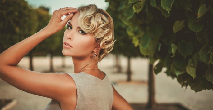 Elegant woman with short curly hair and her hand touching her head