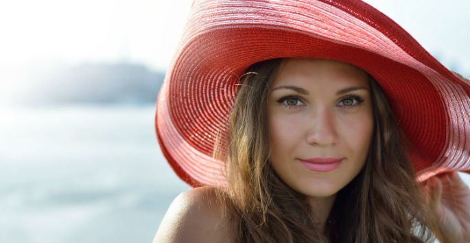 Beautiful woman wearing a wide brim red beach straw hat