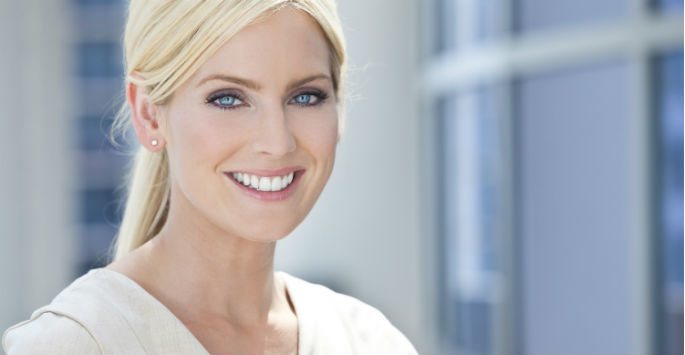 Beautiful blonde woman with blue eyes wearing white blouse