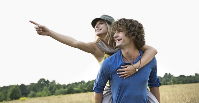 Young couple outdoor photo, woman is carried on back of the man