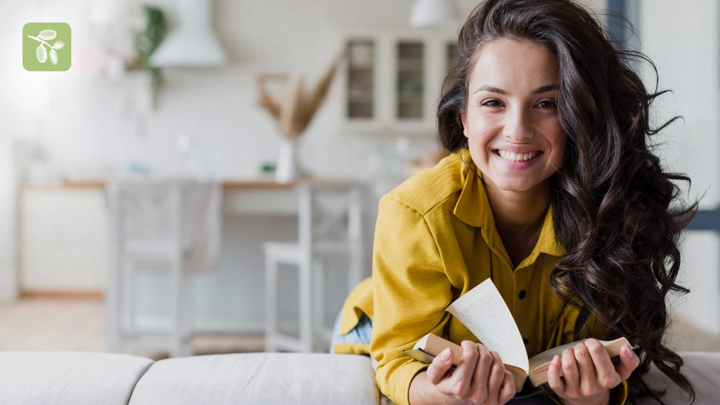 Young happy lady with long curly hair, with a book in her hands