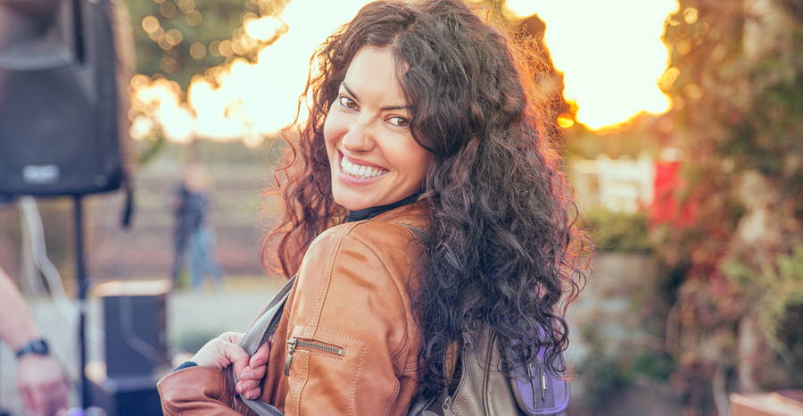 Happy female with curly hair wearing leather jacket and a backpack