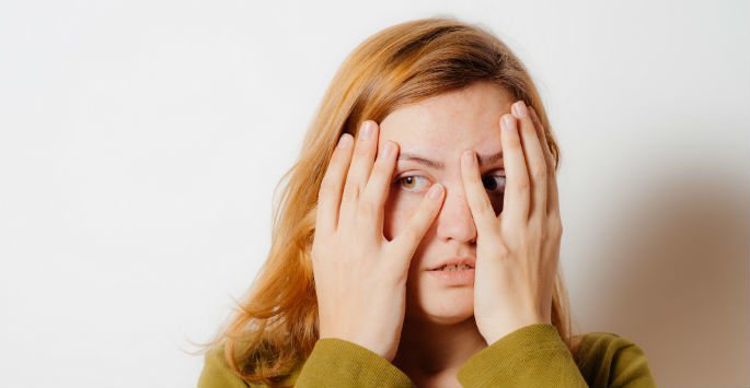 Red hair female peeking through her hands