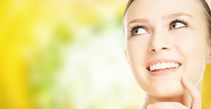 Photo of a woman against yellow lime background with her fingers on her chin