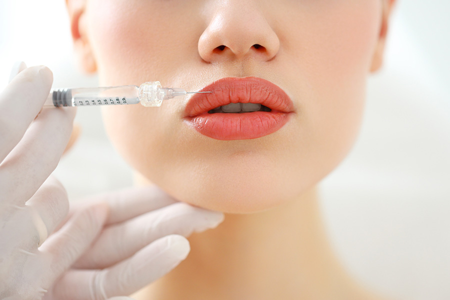 Closeup of crop anonymous female patient getting filler injection in lips in cosmetology clinic