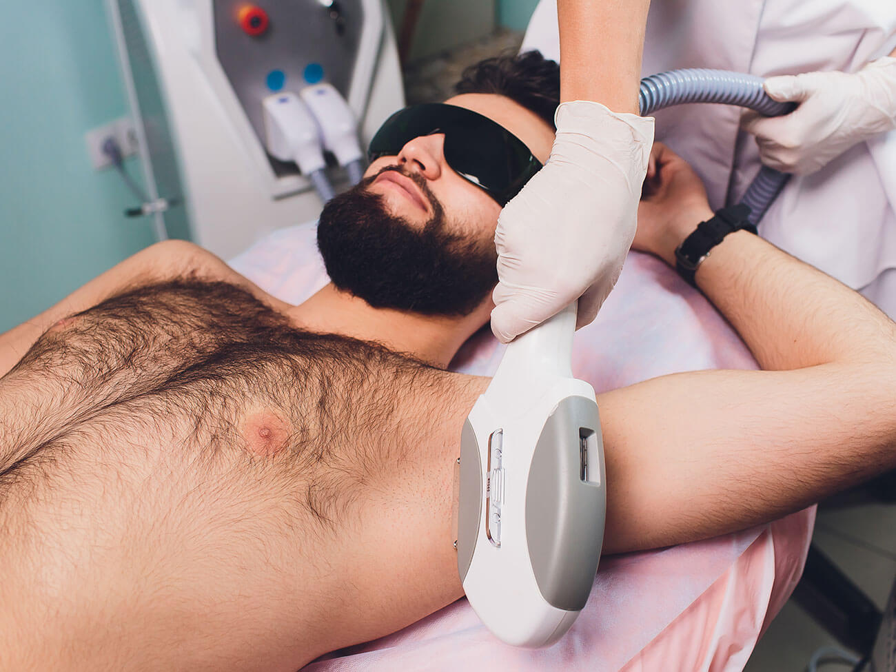 Man lying at beautician's during laser armpit hair removal therapy.